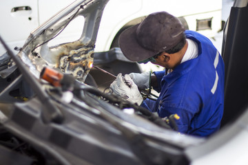 Man mechanical worker repairing a car body in a garage