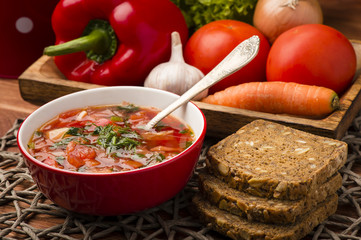 Borscht - traditional russian and ukranian beetroot soup in red bowl on wooden background.