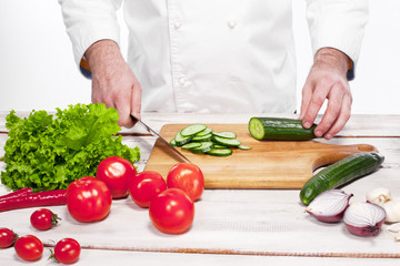 Chef cutting a green cucumber in his kitchen