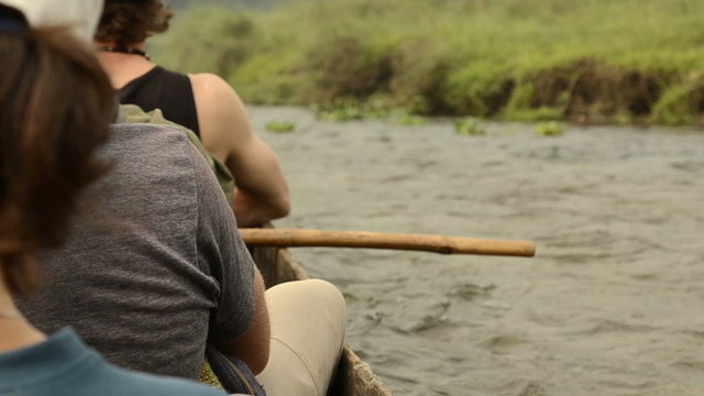 Tourists float on a wooden canoe