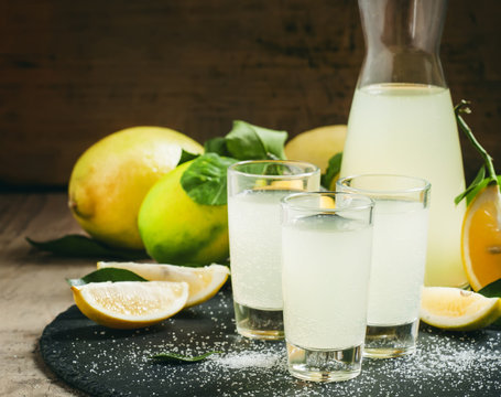 Homemade lemonade with lemon, lime, sugar and soda on a dark bac