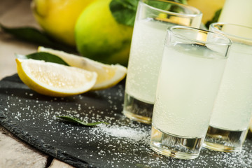 Homemade lemonade with lemon, lime, sugar and soda on a dark bac