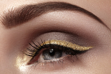Beautiful macro shot of female eye with ceremonial makeup. Perfect shape of eyebrows, eyeliner and...