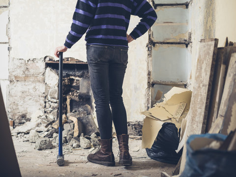 Woman standing by fireplace with sledge hammer