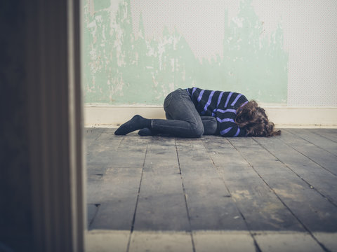 Sad young woman lying on floor