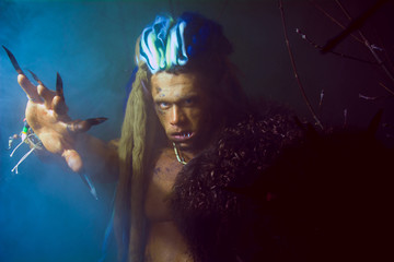 Werewolf with long nails and crooked teeth among the branches of
