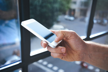 Man using mobile smart-phone near the window, closeup