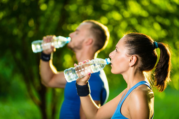 Man and woman drinking water from bottle after fitness sport exercise
