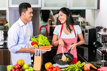 Asian man and woman cooking together