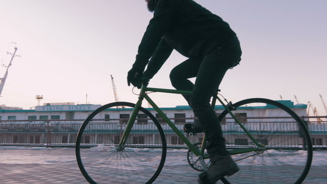 Guy riding fixed gear bike on background of the port, 4k
