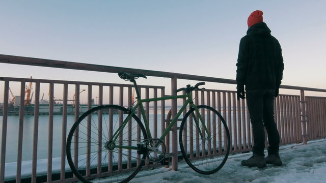 Guy riding fixed gear bike on background of the port, 4k
