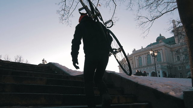 Guy carrying a fixed gear bike and climbing up the steps,super slow motion