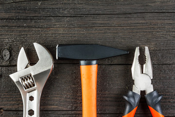 Spanner, hammer and pliers on wood