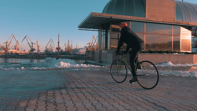 Guy riding fixed gear bike in marine station, slow motion