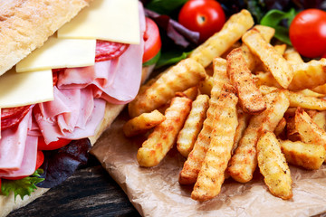 Fried Potatoes and Sandwich with lettuce, slices of fresh tomatoes, salami, hum and cheese.