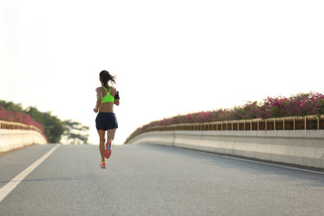 young woman runner running on city bridge road