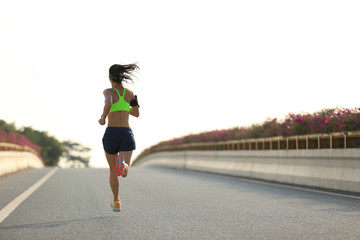 young woman runner running on city bridge road