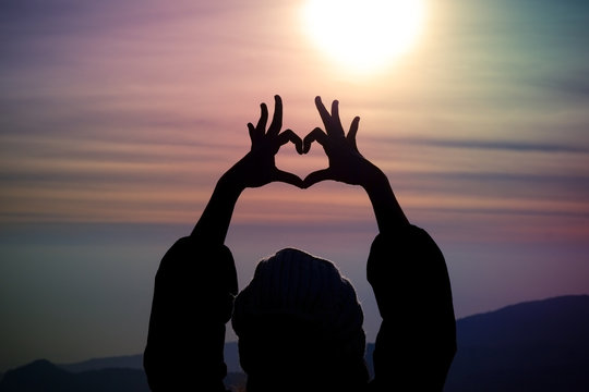 Love shape hand silhouette in the sky