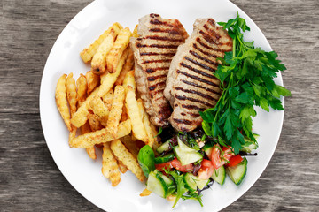 Grilled pork meat  with fried potatoes and vegetables