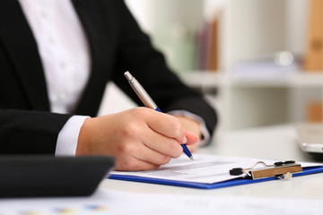 Hand of businesswoman filling and signing with silver pen partne