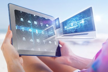 Woman sitting on beach in deck chair using tablet