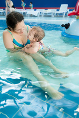 Mother talks little daughter something in water