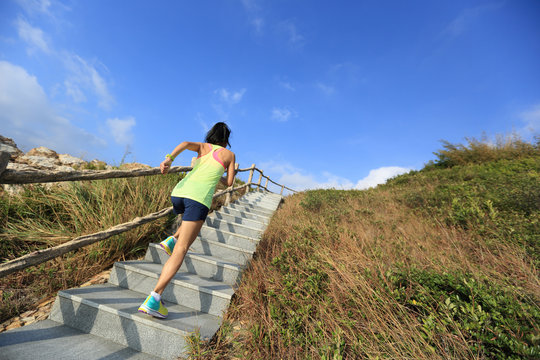 young fitness woman trail runner running up on mountain stairs