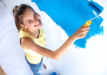 Happy beautiful young woman doing wall painting