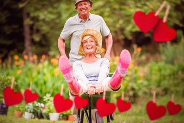 Happy senior couple playing with a wheelbarrow