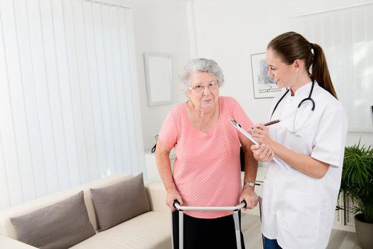 Young Doctor Checking Rehab Medical Progress To An Elderly Woman At Home