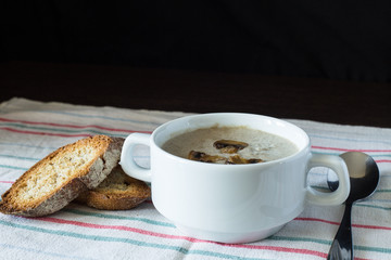Bowl of mushroom soup with bread on wooden board. Recipe or menu background