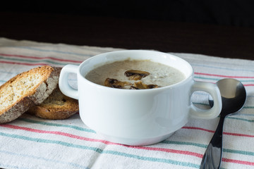Bowl of mushroom soup with bread on wooden board. Recipe or menu background