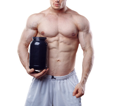 Bodybuilder holding a black plastic jar with whey protein on white background. No face