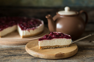 Classic New York style cheesecake with teapot. Slice of sweet on wooden table
