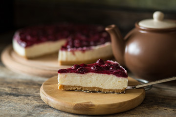 Classic New York style cheesecake with teapot. Slice of sweet on wooden table
