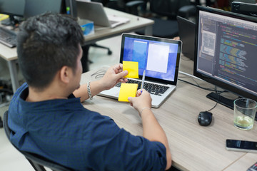 Asian business man yellow sticky note, rear back view thinking idea computer developer working desk...