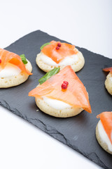 fish salmon slices on pancakes with cream, view from above on the side, close, color image. an appetizer for a party