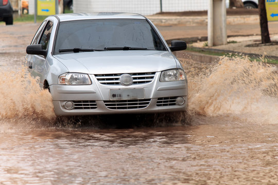 Silver car crossing flooded street after rains