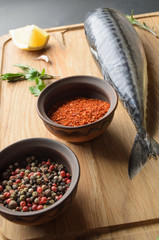 Spice for baking scomber fillets, include raw mackerel, lemon, garlic, pepper, rosemary, from above on wooden cutting board. Rustic style..