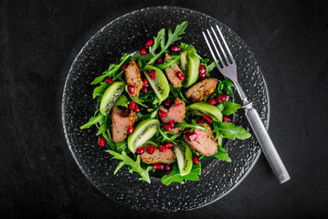 Salad appetizer with chicken liver, arugula, kiwi and pomegranate