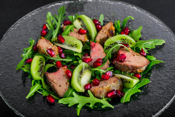 Salad appetizer with chicken liver, arugula, kiwi and pomegranate