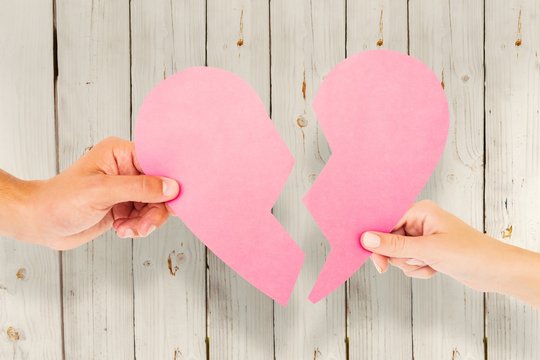 Composite image of couple holding two halves of broken heart