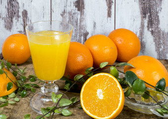 Orangen und frisch gepresster Orangensaft vor alter Holzwand