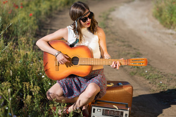 Beautiful woman with a suitcase and a guitar