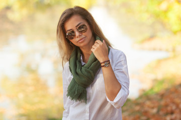 Sunny portrait of a beautiful young woman is sunglasses and in a green scarf