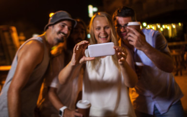 Happy friends making phone selfie at night