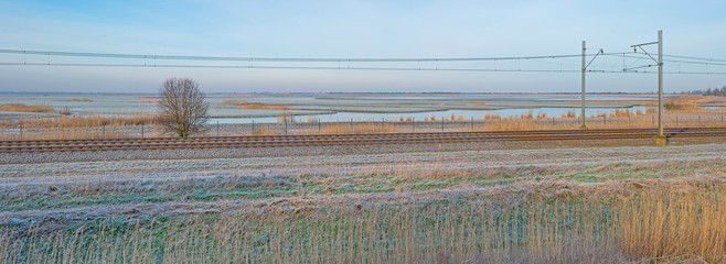 Railroad through sunny frozen nature in winter