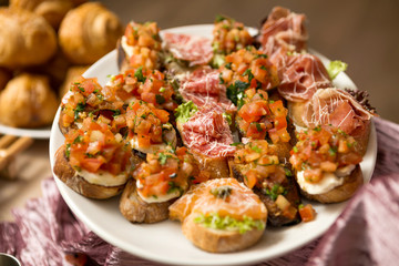 a plate of bruschetta with mozzarella, prosciutto and vegetables