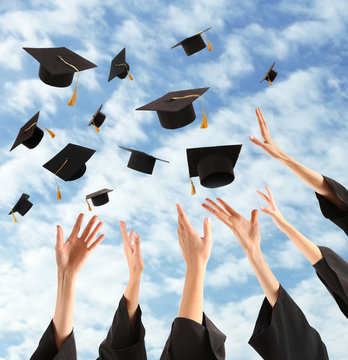 Graduates hands throwing graduation hats in the sky