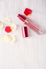 Bottle of perfume and rose petals on fabric background